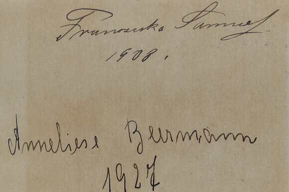 Man sieht ein Stück vergilbtes Papier mit zwei unterschriften darauf. Oben steh Franziska Samuel und darunter 1908. Dann mit etwas Abstand dazwischen weiter unten steht Anneliese Beermann und daraunter 1927